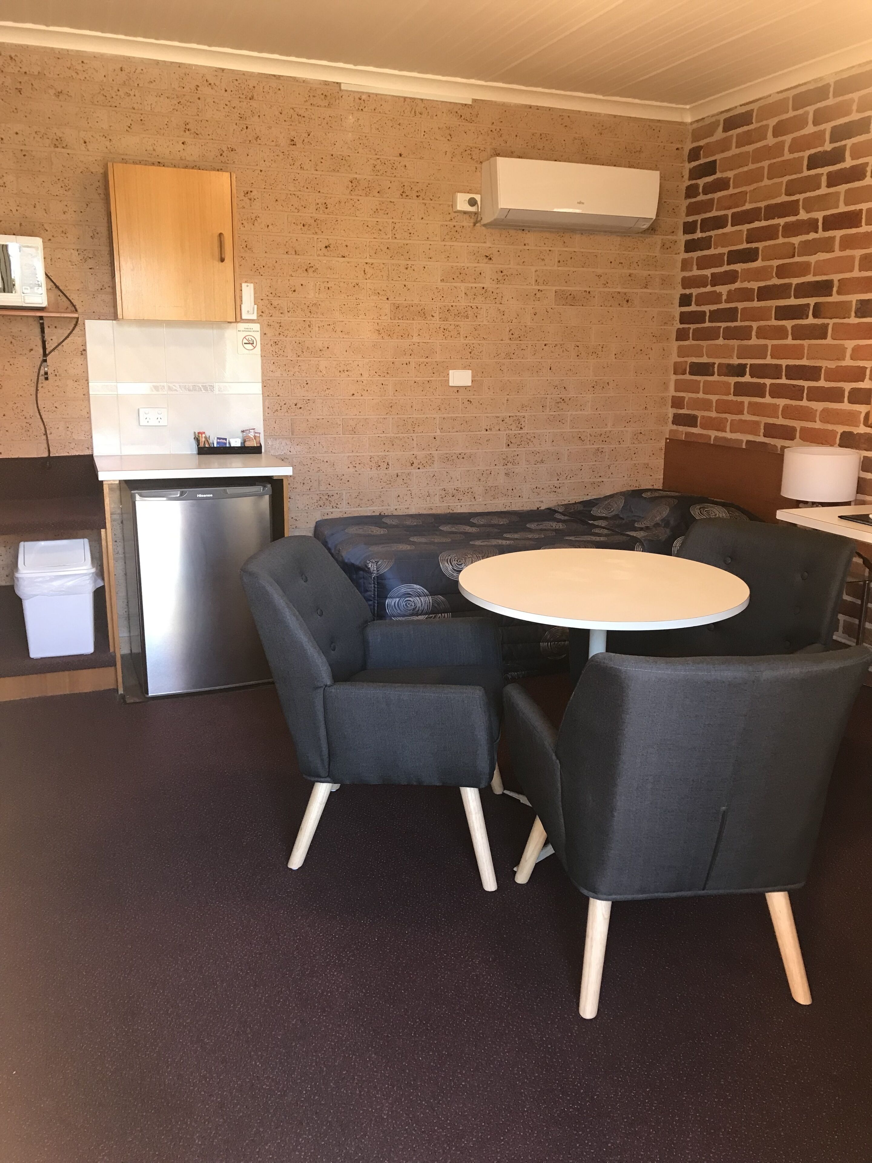 A compact room with a kitchenette, a sofa, a small table, and a single chair.