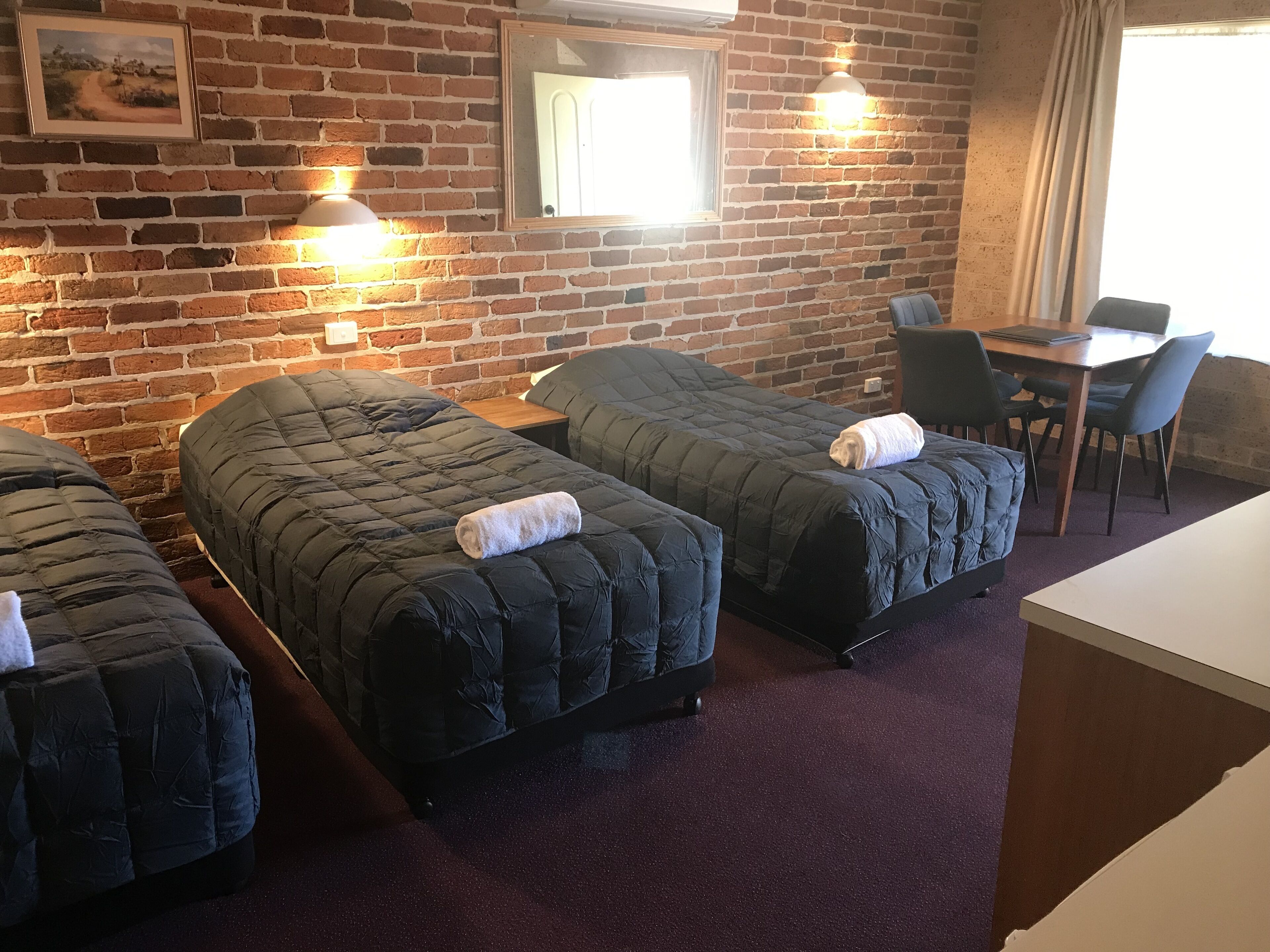 A room with three beds, a wooden table, and chairs.