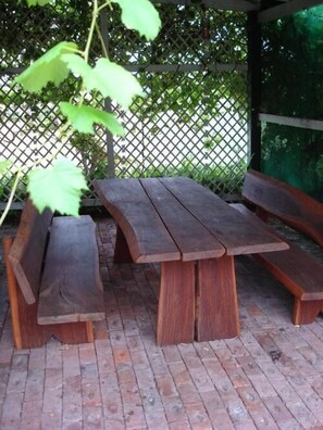 A wooden picnic table with benches, set on a brick patio with a lattice fence in the background. - Lochinvar House B&B (Lochinvar)