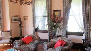 A traditional living room with two floral armchairs, a wooden coffee table, and a chandelier. - Lochinvar House B&B (Lochinvar)