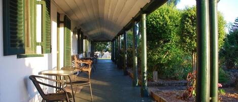 A covered outdoor area with tables and chairs, a pathway, and greenery.
