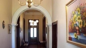 A hallway with a chandelier, a painting of sunflowers, and a patterned rug. - Lochinvar House B&B (Lochinvar)