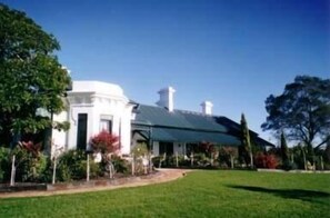 A white building with a green roof, surrounded by a well-maintained lawn and trees. - Lochinvar House B&B (Lochinvar)