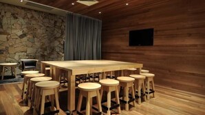 A conference room with a long table and multiple stools, a stone wall, and a wooden ceiling. - The Mansfield Park Hotel (Mansfield Park)
