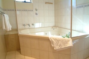 A bathroom with a large bathtub, a mirror, and a towel rack.