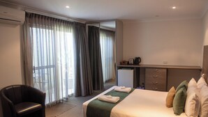 A hotel room with a bed, a chair, a desk with a computer, and a window with curtains. - Victoria Hotel - Strathalbyn (Strathalbyn)