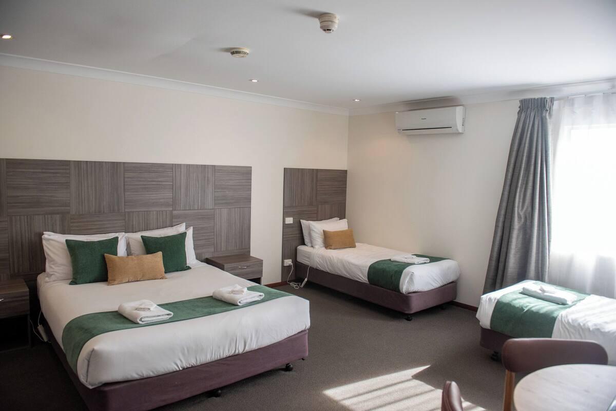 A hotel room with two beds, a desk, and a chair.