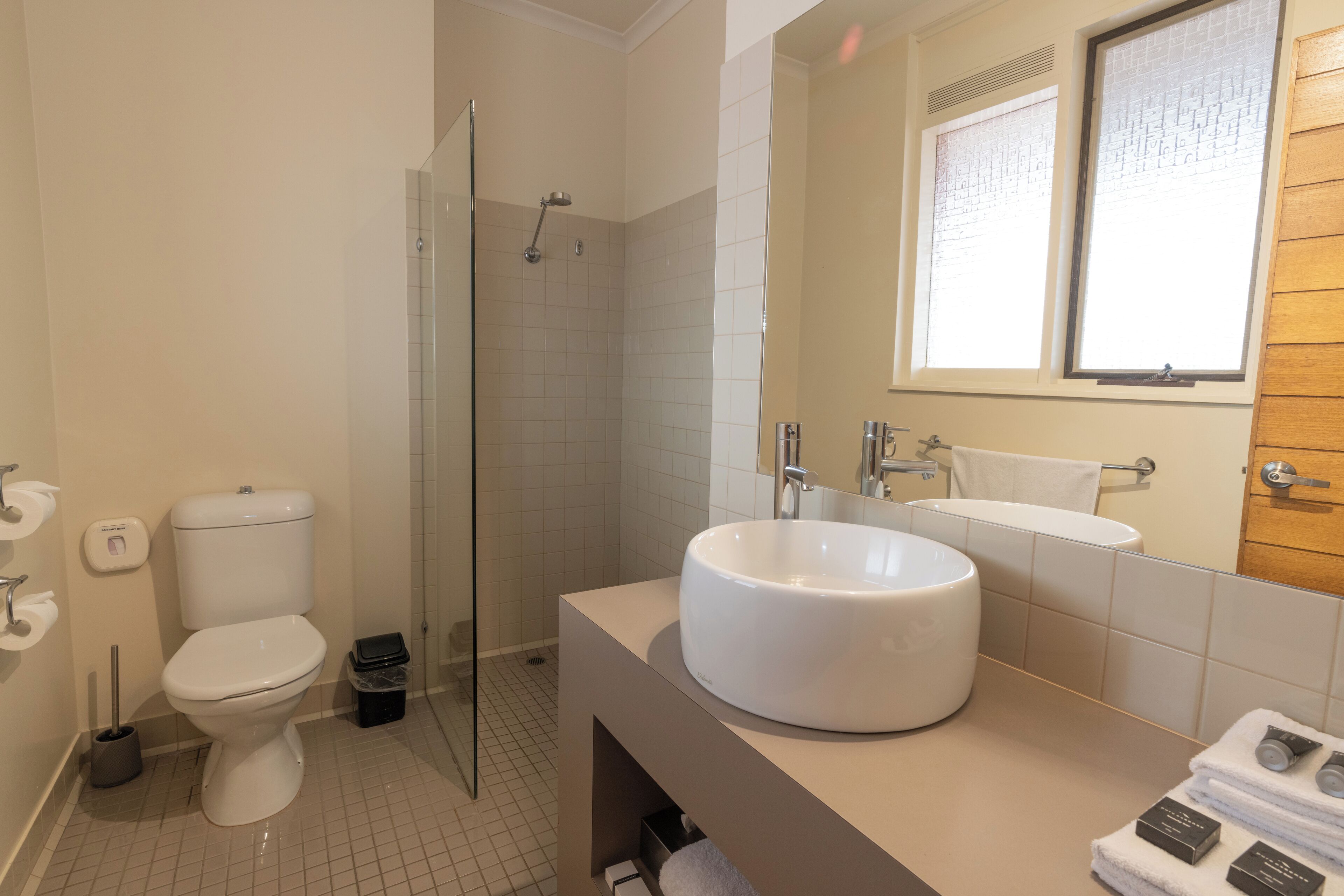 A modern bathroom with a toilet, a glass-enclosed shower, a sink, and a mirror.