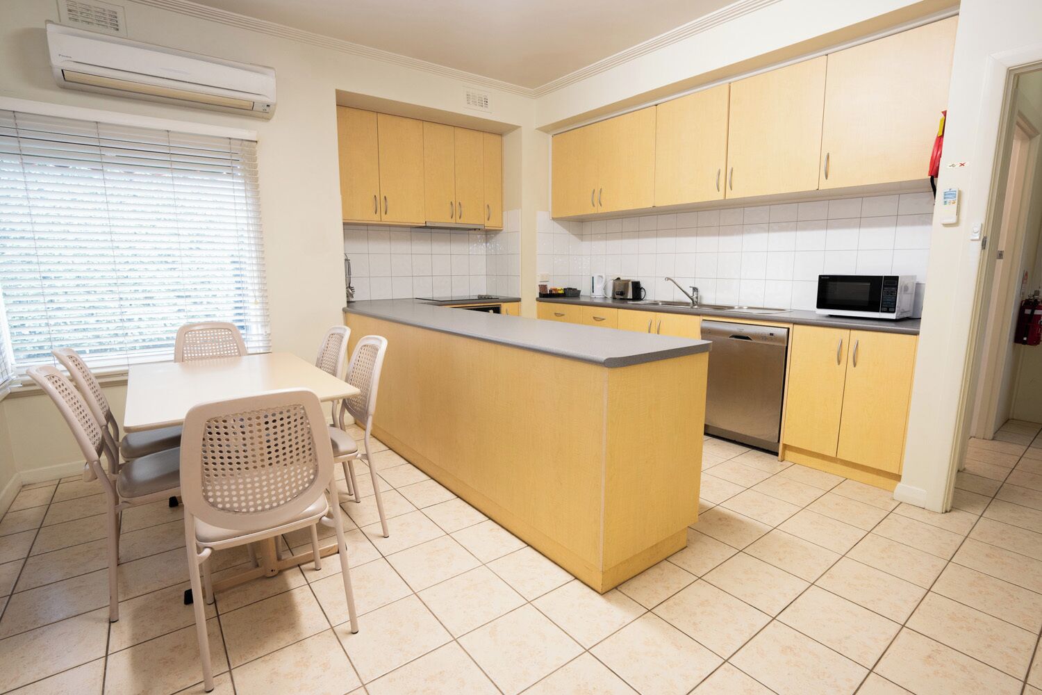 A kitchen with yellow cabinets, a central island, a dining table with chairs, and a microwave.