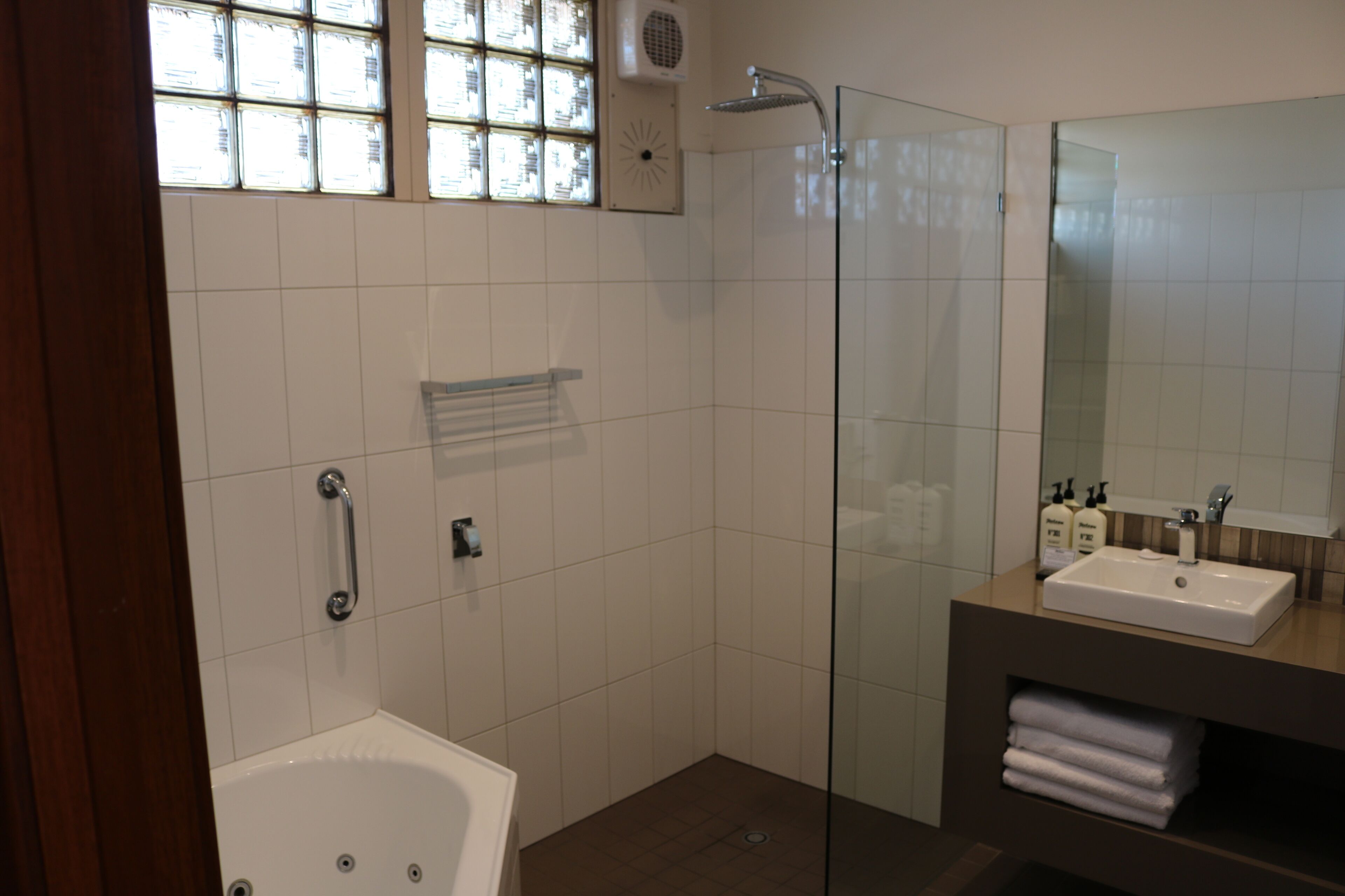 A modern bathroom with a glass-enclosed shower, a bathtub, and a vanity with a sink and mirror.