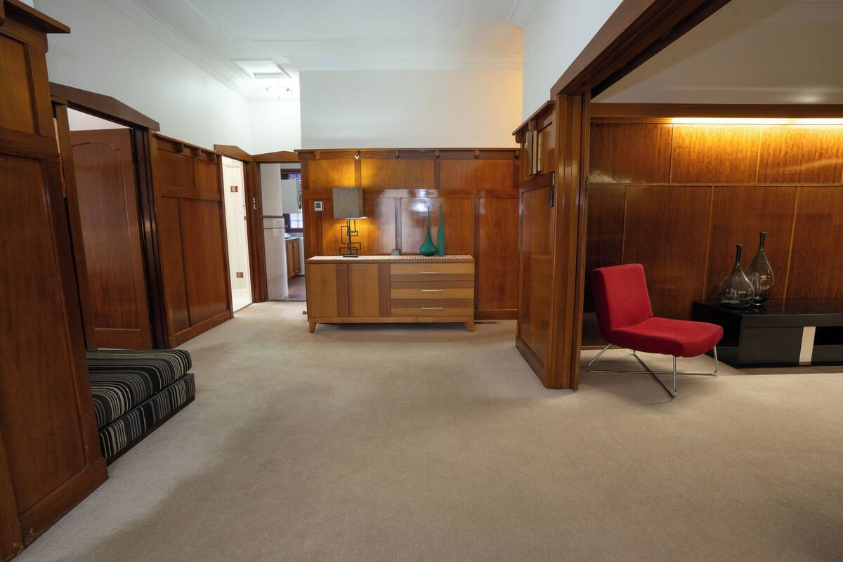 A spacious room with a wooden cabinet, a red chair, and a small table with decorative items.