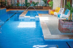 Una piscina interior con agua cristalina, una fuente y sillas de descanso coloridas.