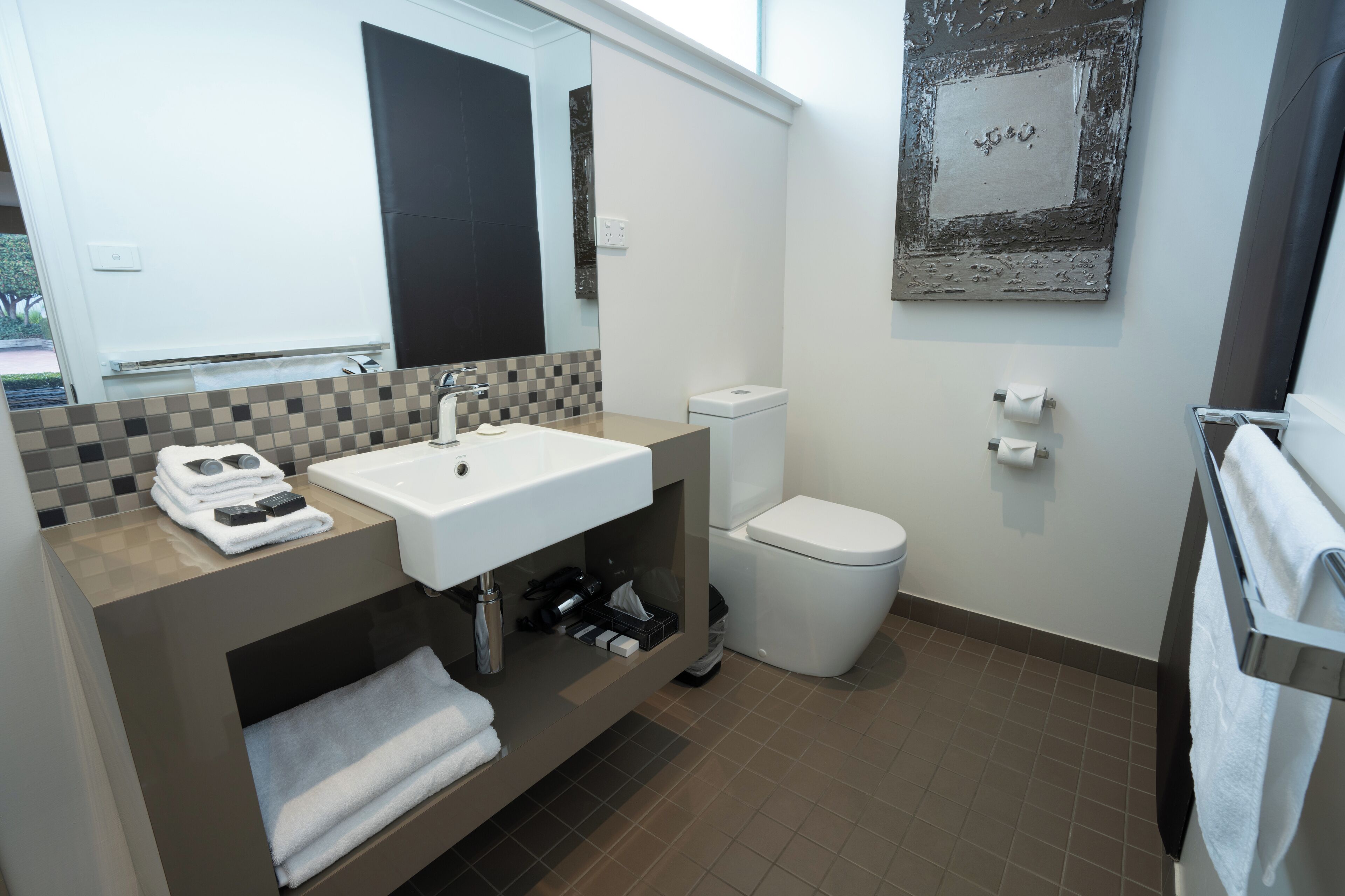 Un baño moderno con lavamanos, inodoro y perchero para toallas.