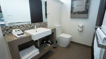 Un baño moderno con lavamanos, inodoro y perchero para toallas.