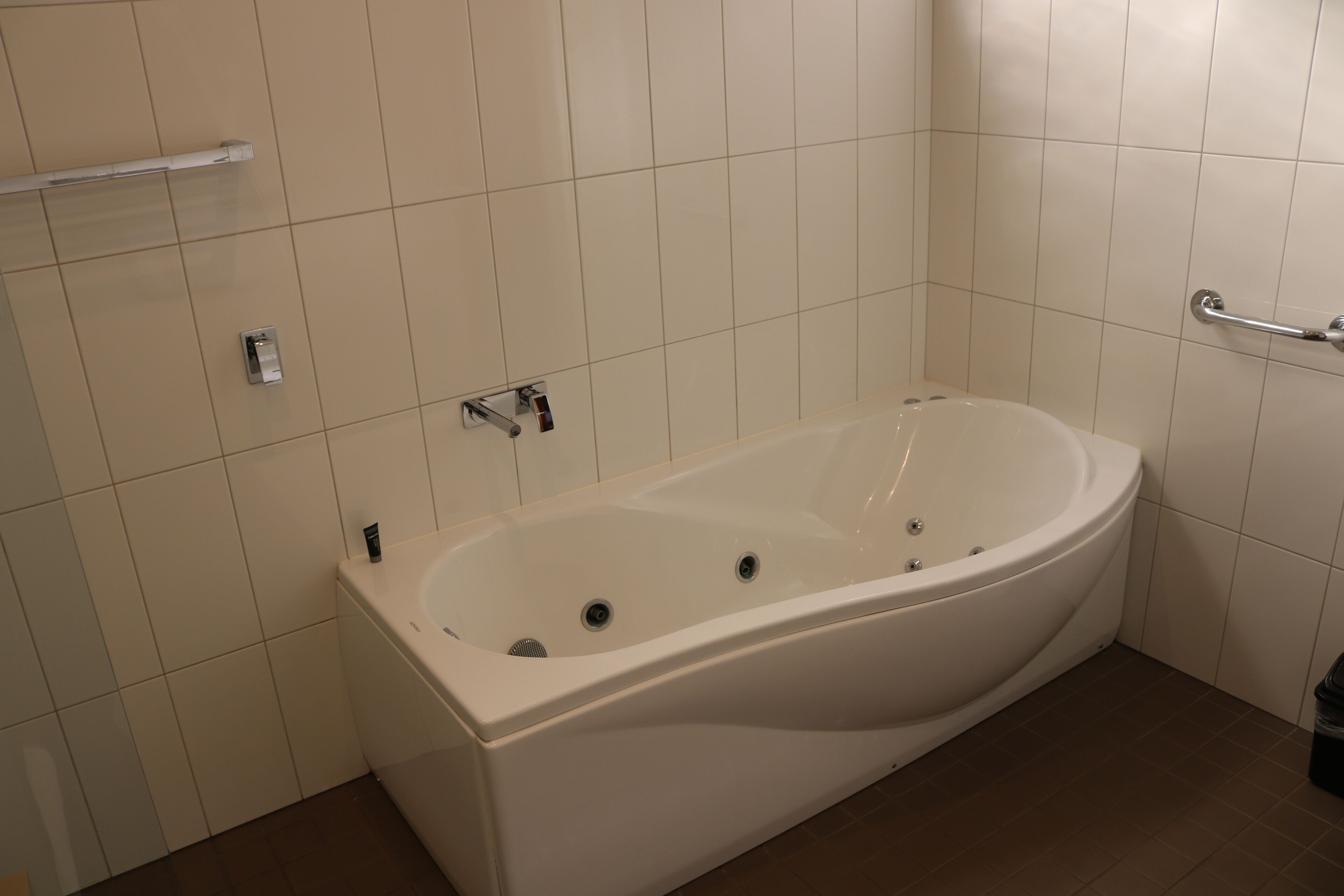 Un baño moderno con una bañera independiente, un pasamanos y un perchero para toallas.