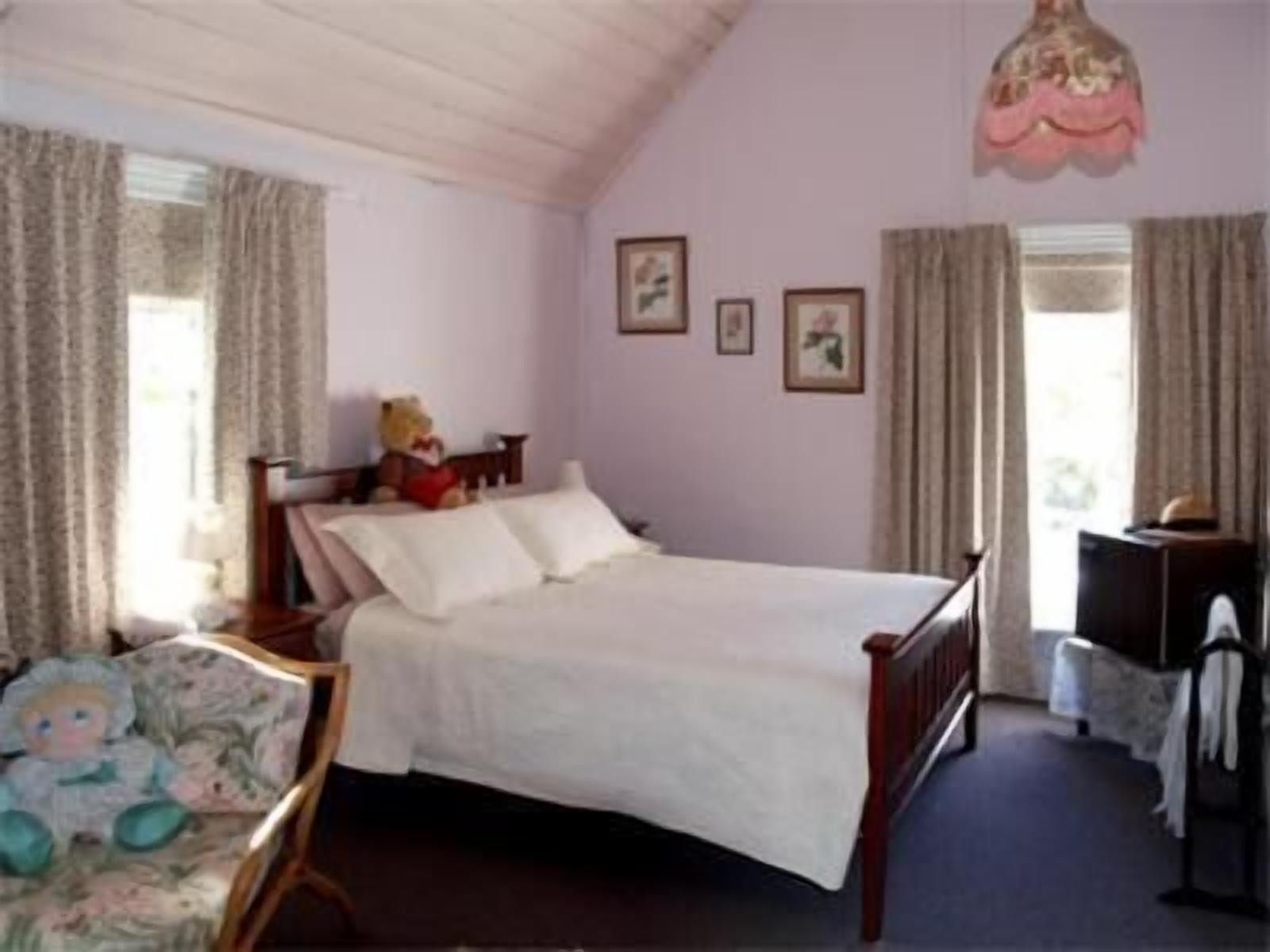 A bedroom with a bed, a chair, a dresser, and a window with curtains.