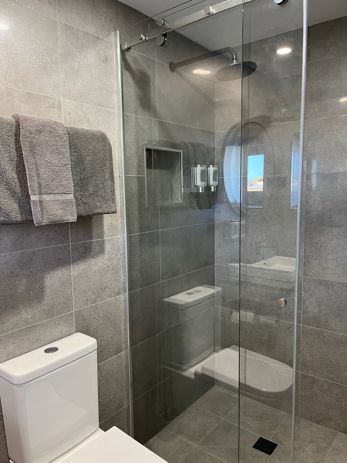 Ein modernes Badezimmer mit einer gläsernen Duschkabine, einer Toilette und einem Waschbecken.