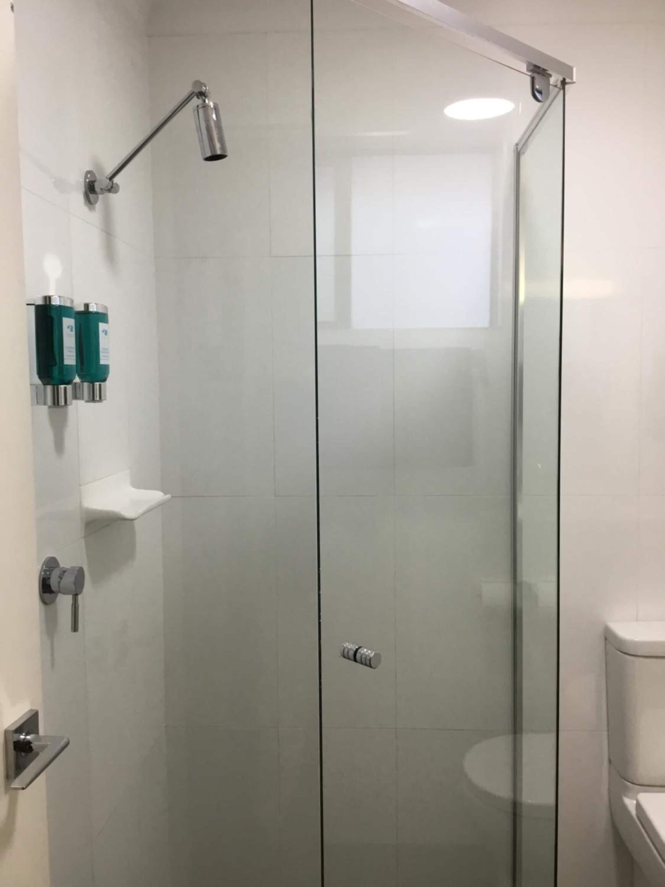 A modern bathroom with a glass shower enclosure, a toilet, and a sink.