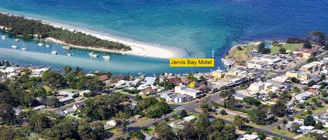 An aerial view of Jervis Bay Motel with a beachfront, surrounding residential area, and clear blue waters.