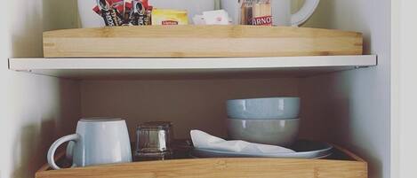 Eine Küche mit einem weißen Kühlschrank, einer Kaffeemaschine, einem Wasserkocher und verschiedenen Küchenutensilien auf Holzböden.