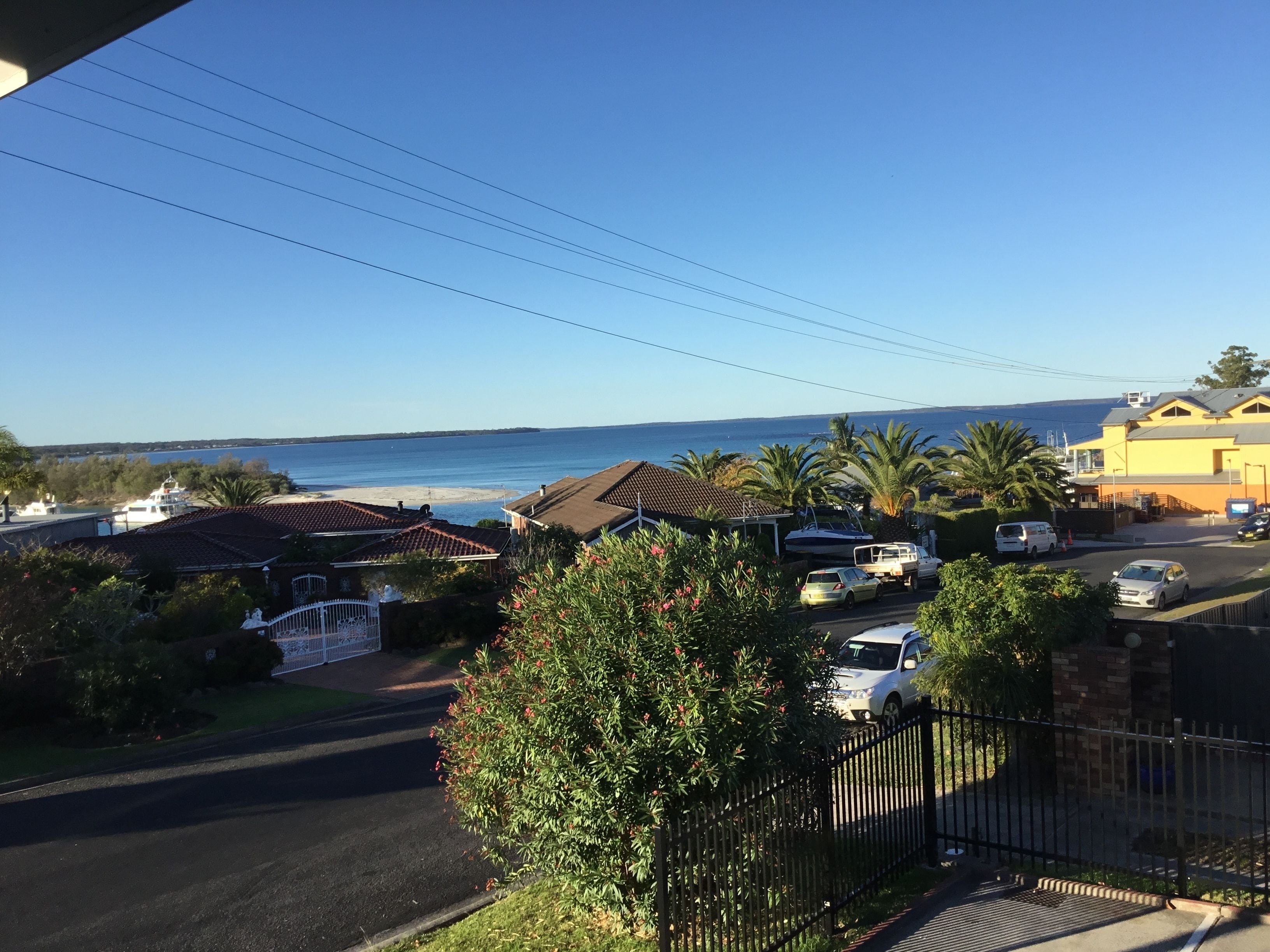 Un quartier résidentiel avec vue sur la mer, des voitures garées et un immeuble jaune.