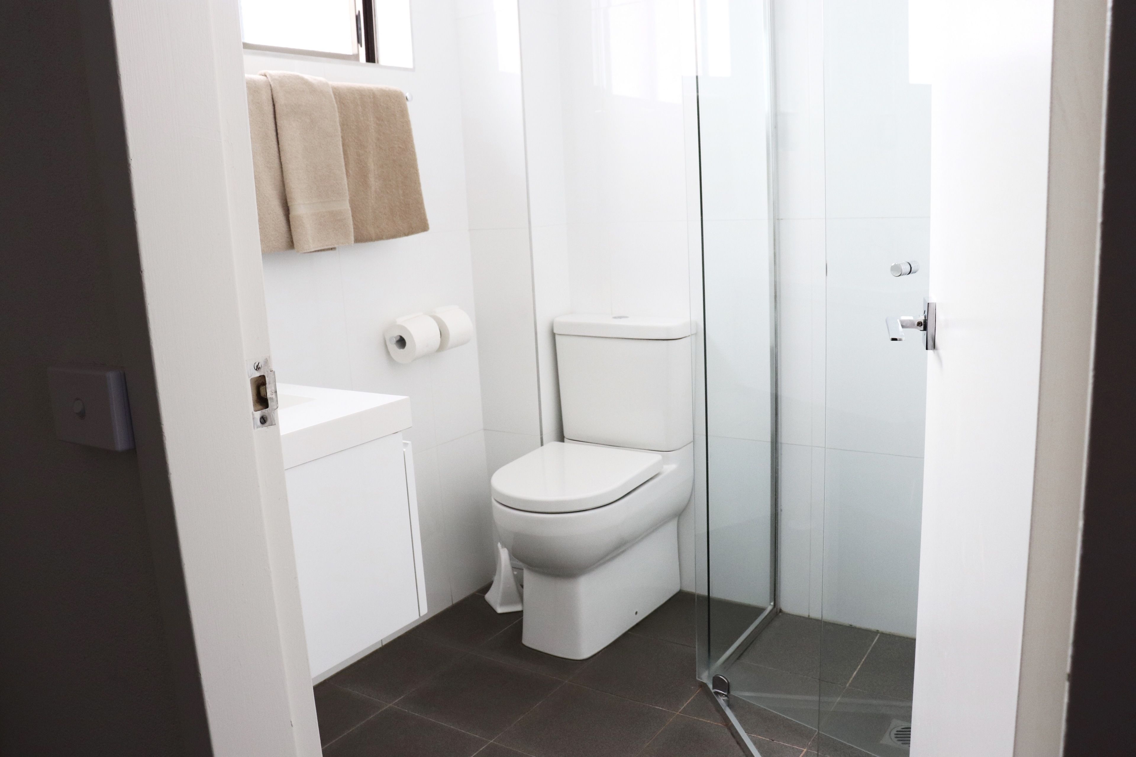 A modern bathroom with a toilet, a sink, and a glass shower enclosure.