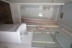 A bathroom with a glass shower enclosure, a white sink, and a towel rack. - Seaforth Holiday Units (Seaforth)