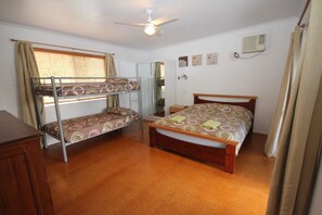 A room with bunk beds, a single bed, a wooden desk, and a ceiling fan. - Seaforth Holiday Units (Seaforth)