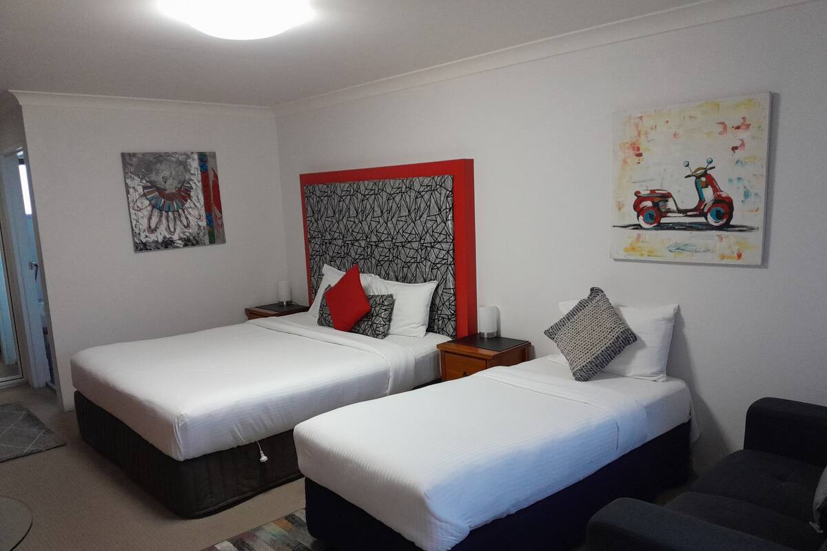 A hotel room with two beds, a small sofa, and artwork on the walls.