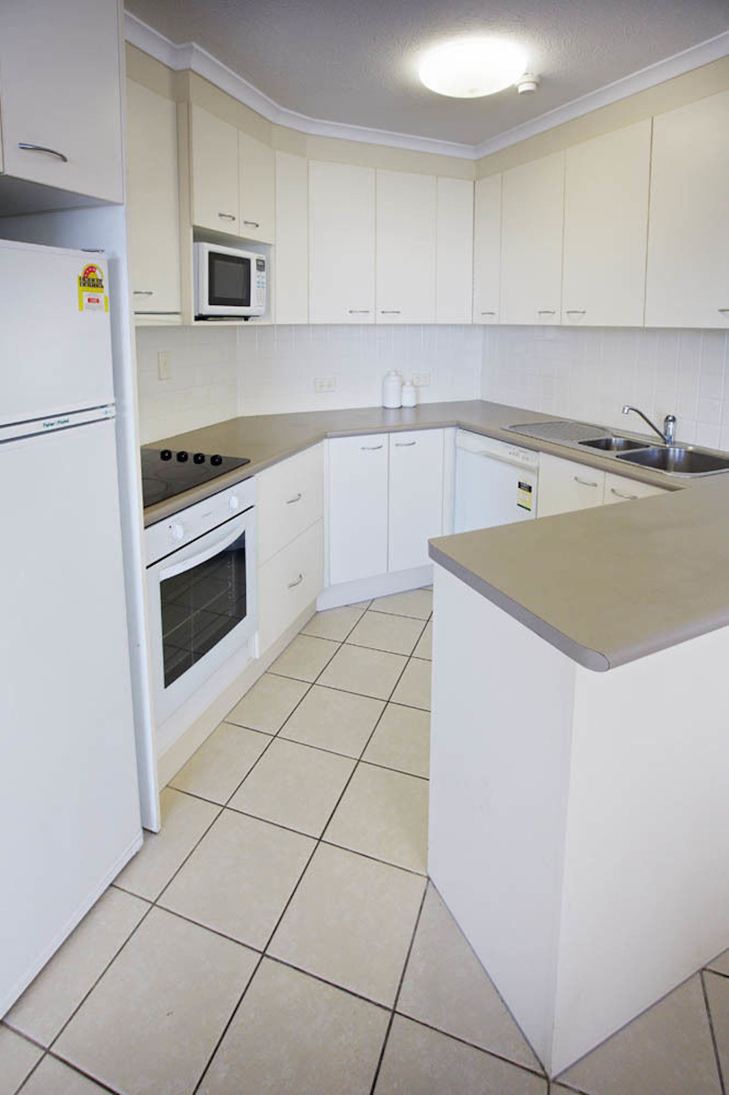 A compact kitchen with white cabinets, a microwave, a stove, and a dishwasher.