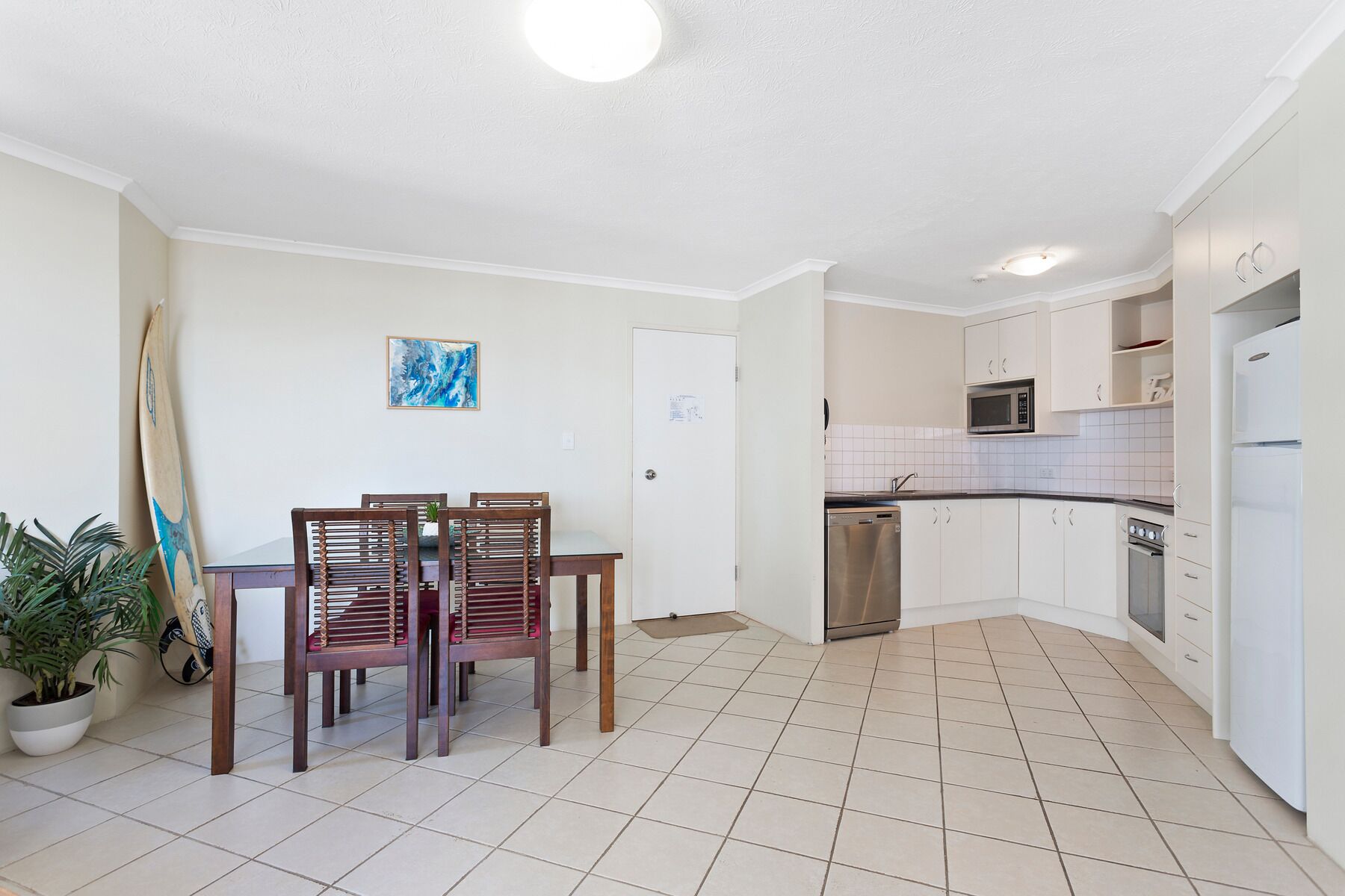 A modern kitchen with white cabinets, a stainless steel dishwasher, and a white refrigerator.