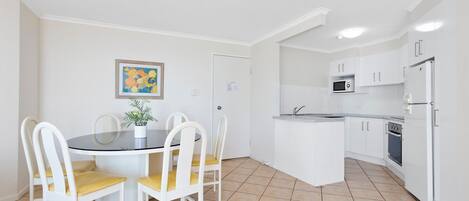 Una cocina compacta con armarios blancos, un microondas y un refrigerador.