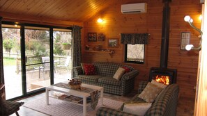 A cozy cabin interior with a plaid sofa, a white coffee table, and a fireplace. - Edelweiss Cottage B&B (Dederang)