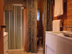 A bathroom with a shower, toilet, sink, and a small animal figure. - Edelweiss Cottage B&B (Dederang)