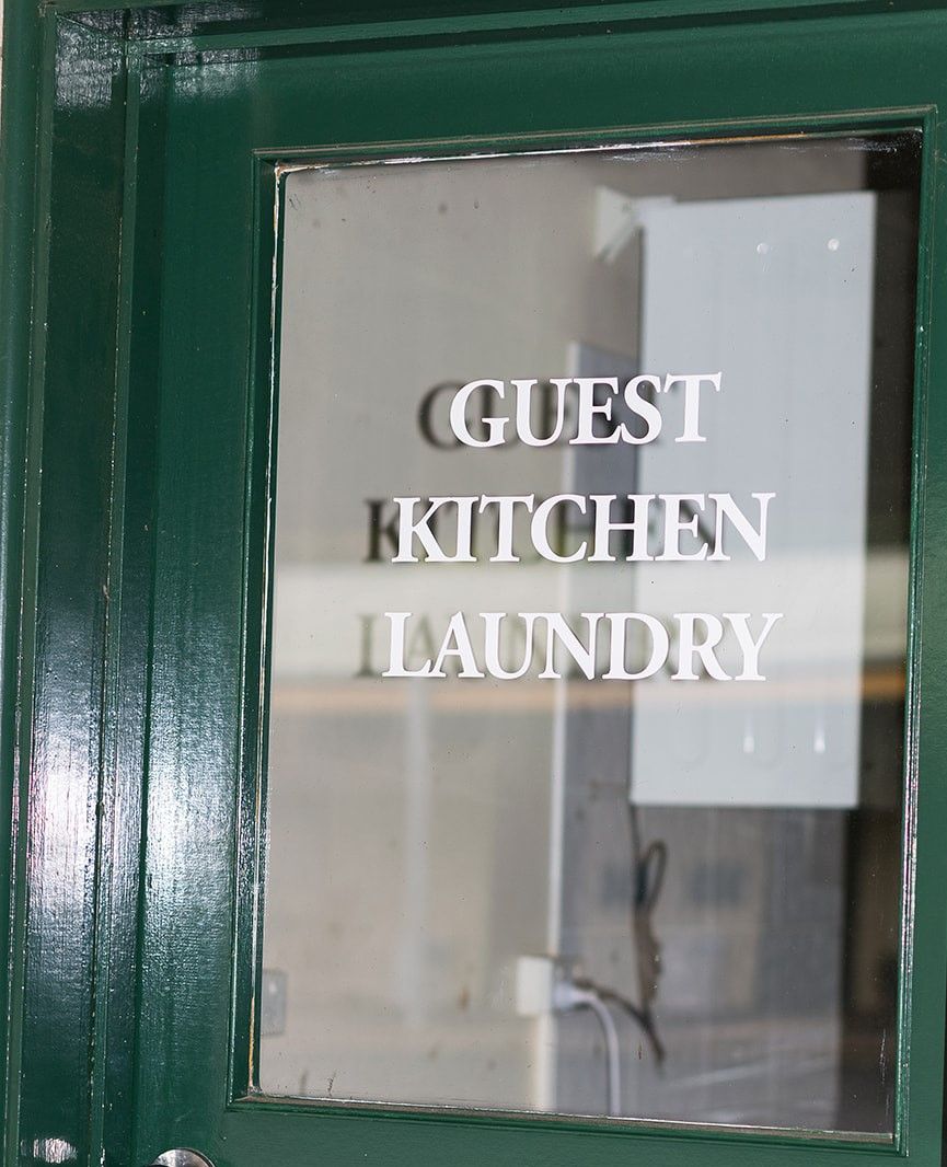 A green-framed window with the text 'GUEST KITCHEN LAUNDRY' indicating a guest kitchen and laundry area.