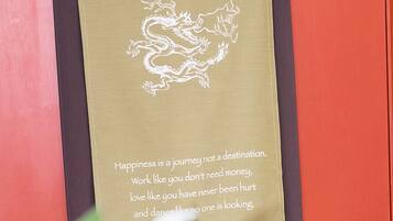 A scroll with a dragon design and inspirational text on a red door.