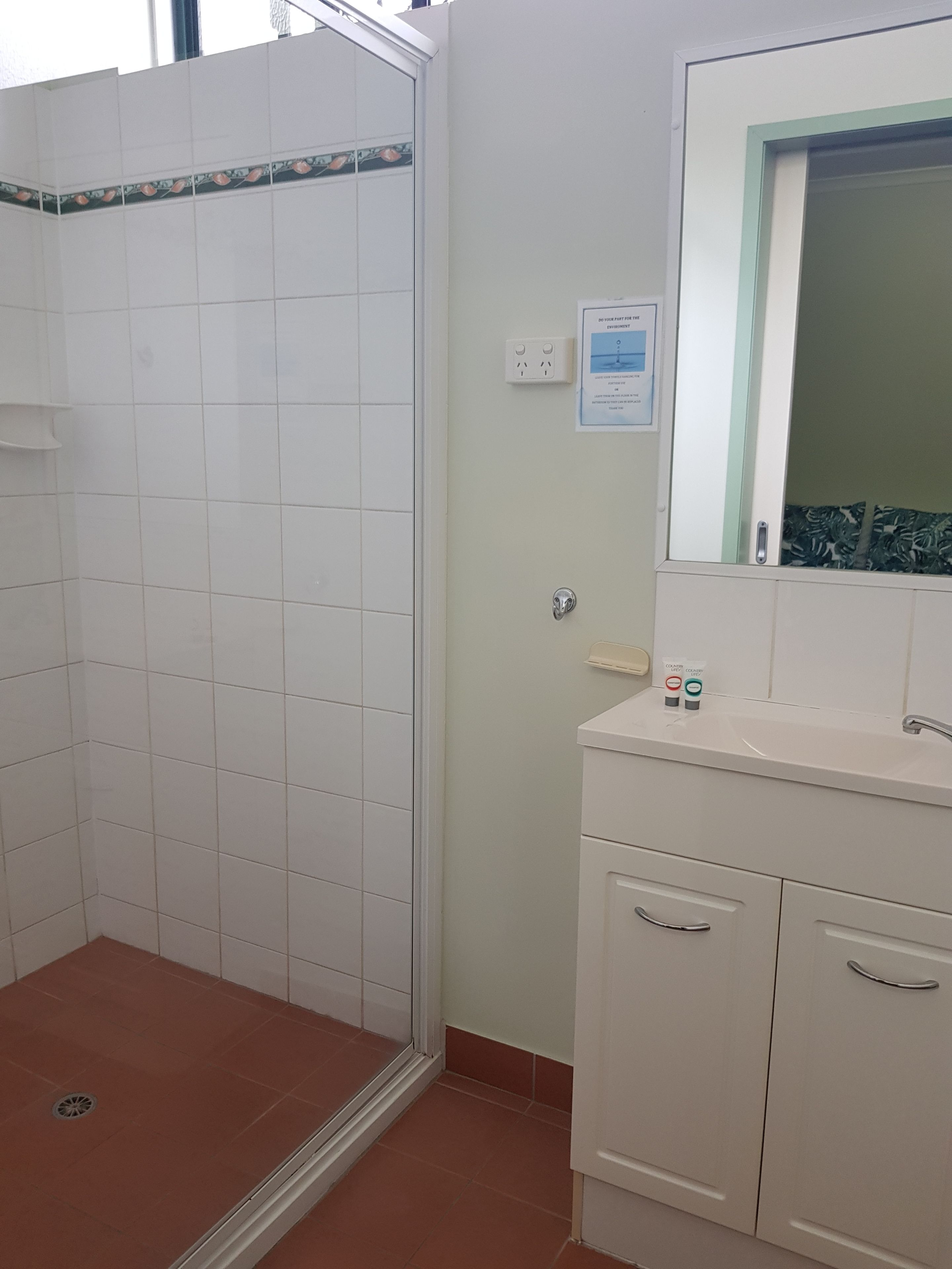 A bathroom with a shower, a sink, and a mirror.