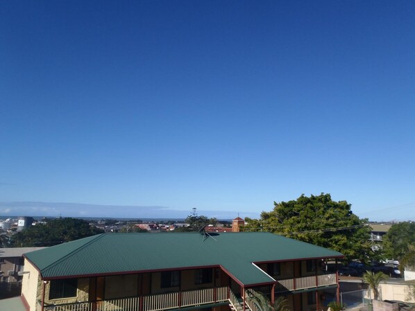 A building with a green roof, a balcony, and a view of a town and mountains in the distance. - Harbour Lodge Motel Gladstone (Gladstone)