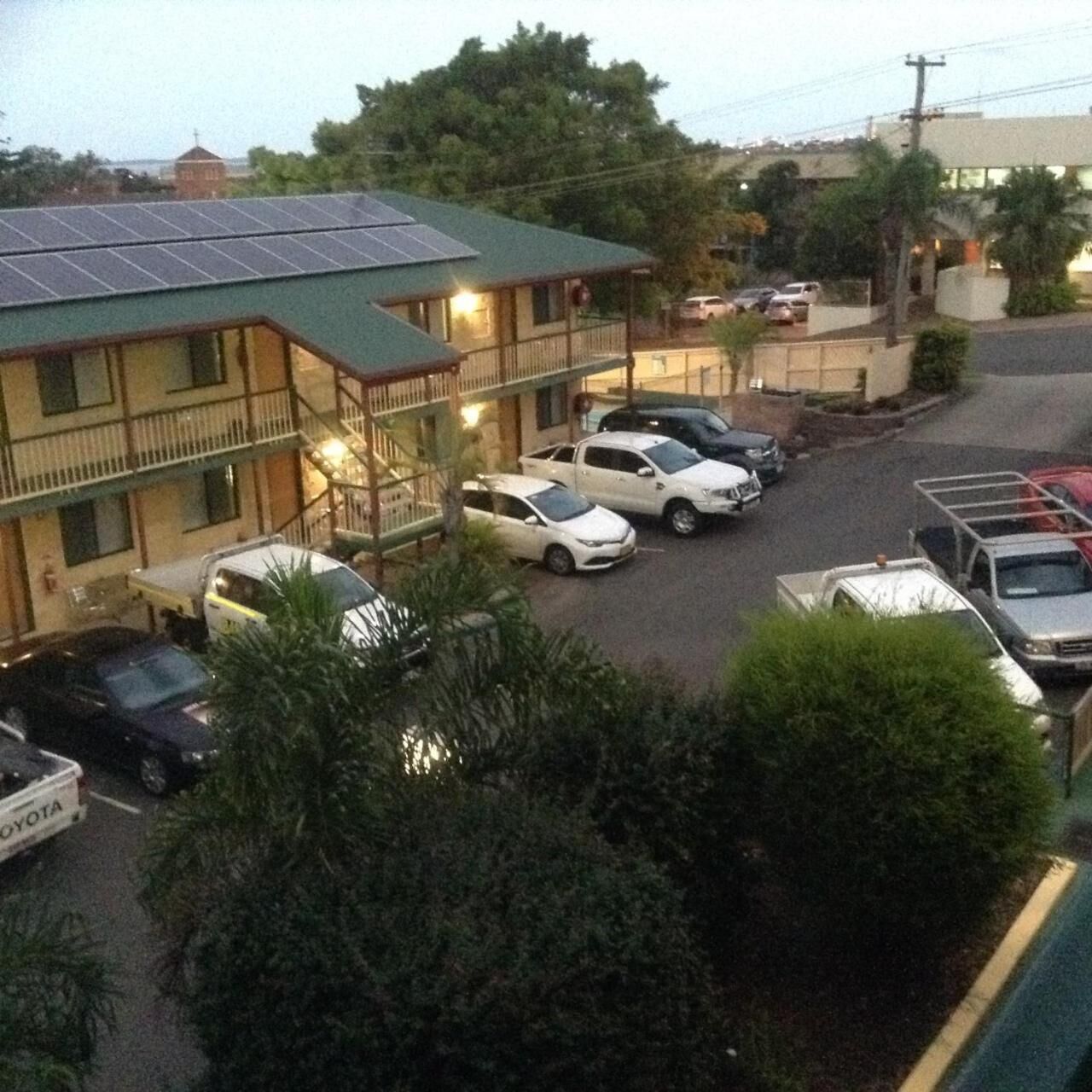 Un hôtel doté d’un toit végétalisé, de plusieurs étages et d’un parking où sont stationnées plusieurs voitures.