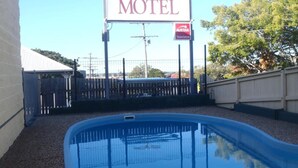 Bord van Harbour Lodge Motel, een zwembad en een omheind gebied met bomen.