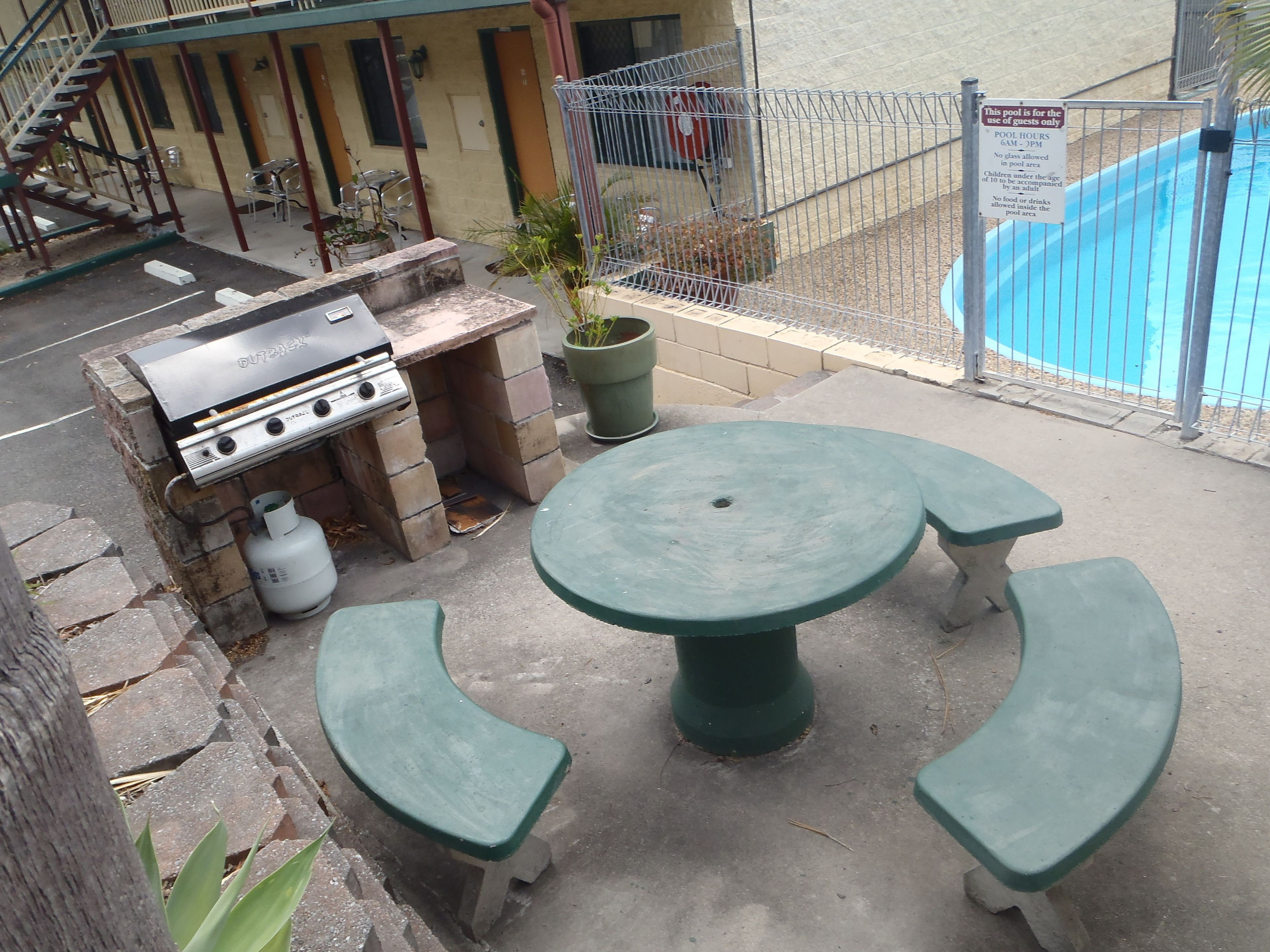 An outdoor patio with a grill, a round table, and two benches.
