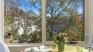 A table with a napkin, a glass of drink, and a vase with flowers. - Topiary Haven (West Launceston)