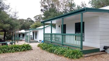 Cabins with porches and railings, set amidst trees.
