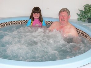 Un homme et un enfant dans un jacuzzi dont les bords sont recouverts de carreaux.