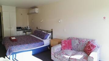 A bedroom with a bed, a sofa, a desk with a chair, and a wardrobe.