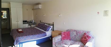 A bedroom with a bed, a sofa, a desk with a chair, and a wardrobe.