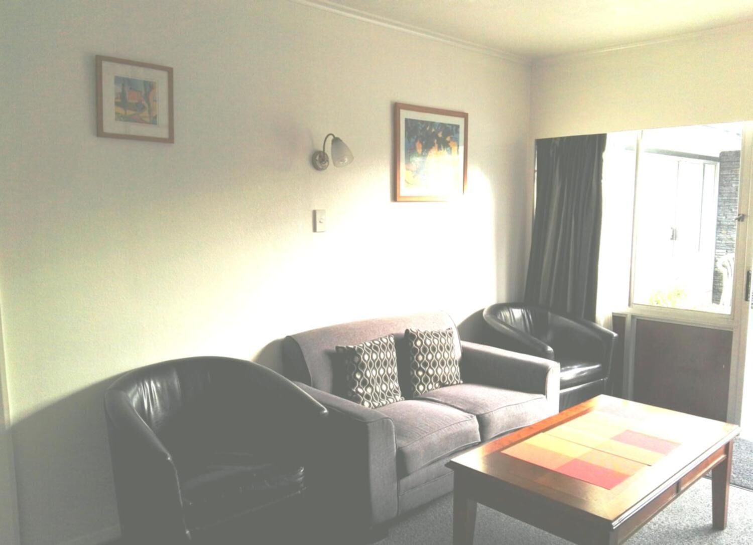 Una sala de estar con un sofá, dos sillones, una mesa de centro y dos lámparas de pared.