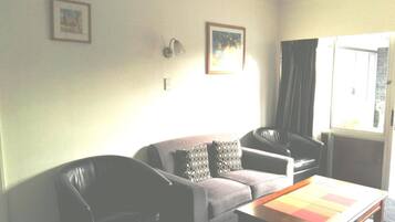A living room with a sofa, two armchairs, a coffee table, and two wall-mounted lamps.