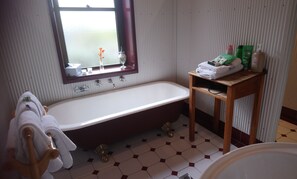 A bathroom with a bathtub, a wooden vanity, and toiletries on the vanity.