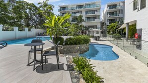 Et moderne hotel med swimmingpool, udendørs siddepladser og frodig beplantning.